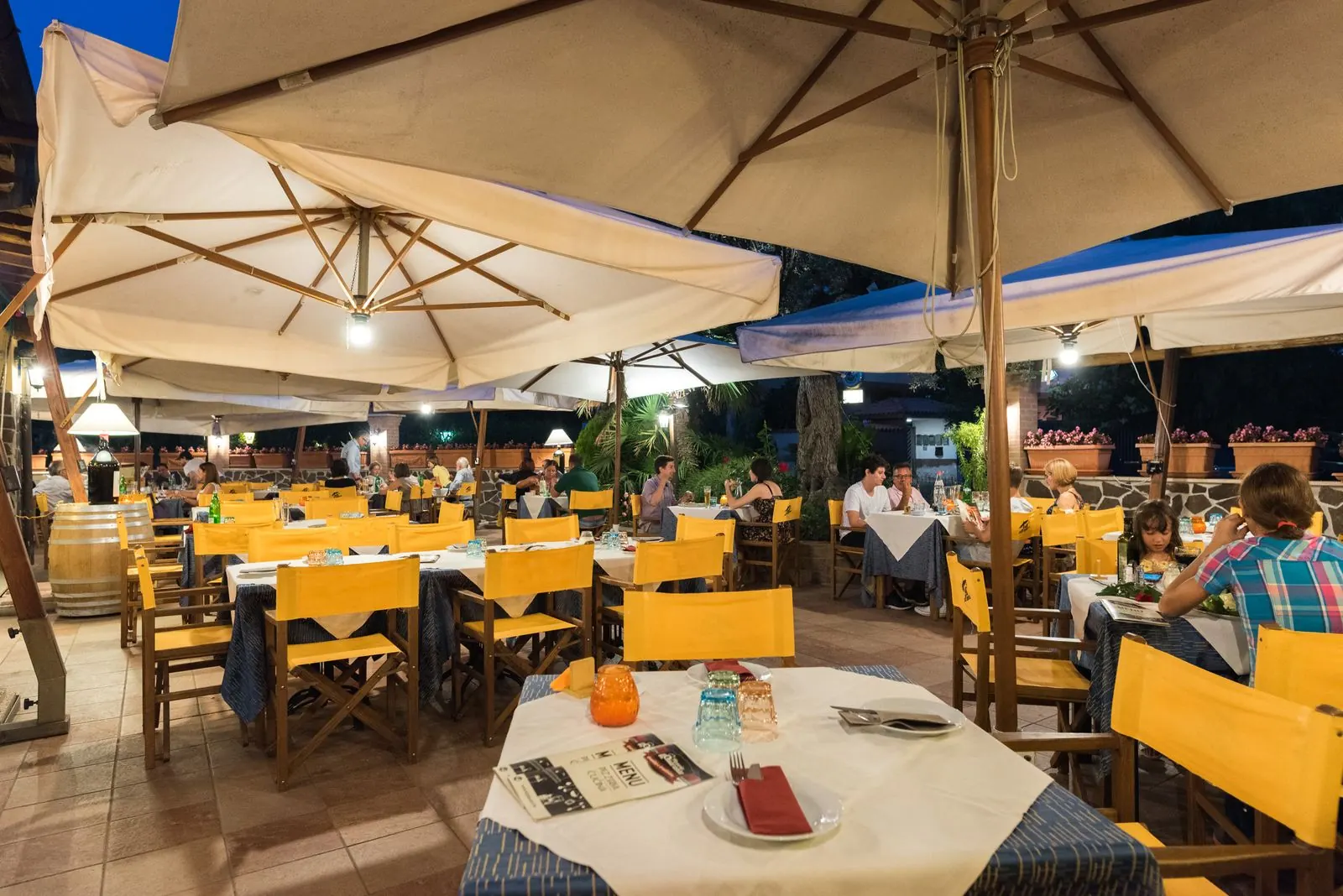 Il giardino di sera con le luci accese e i clienti a tavola