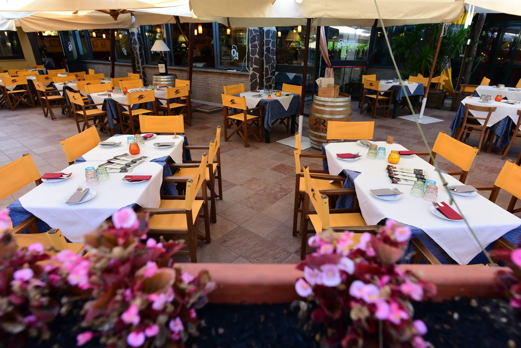 Tavoli apparecchiati in giardino con fiori in primo piano