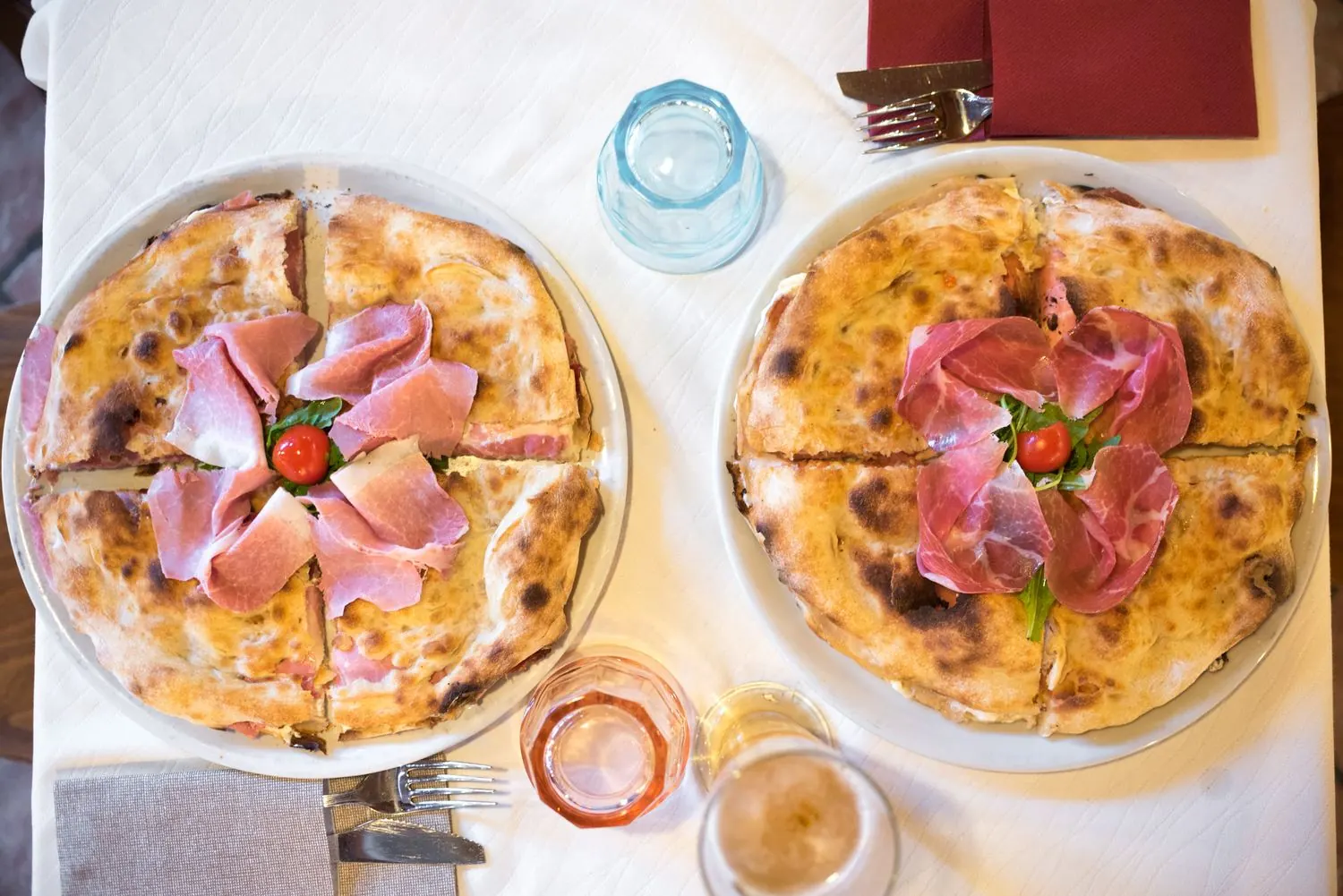 Due pizze con prosciutto crudo in tavola