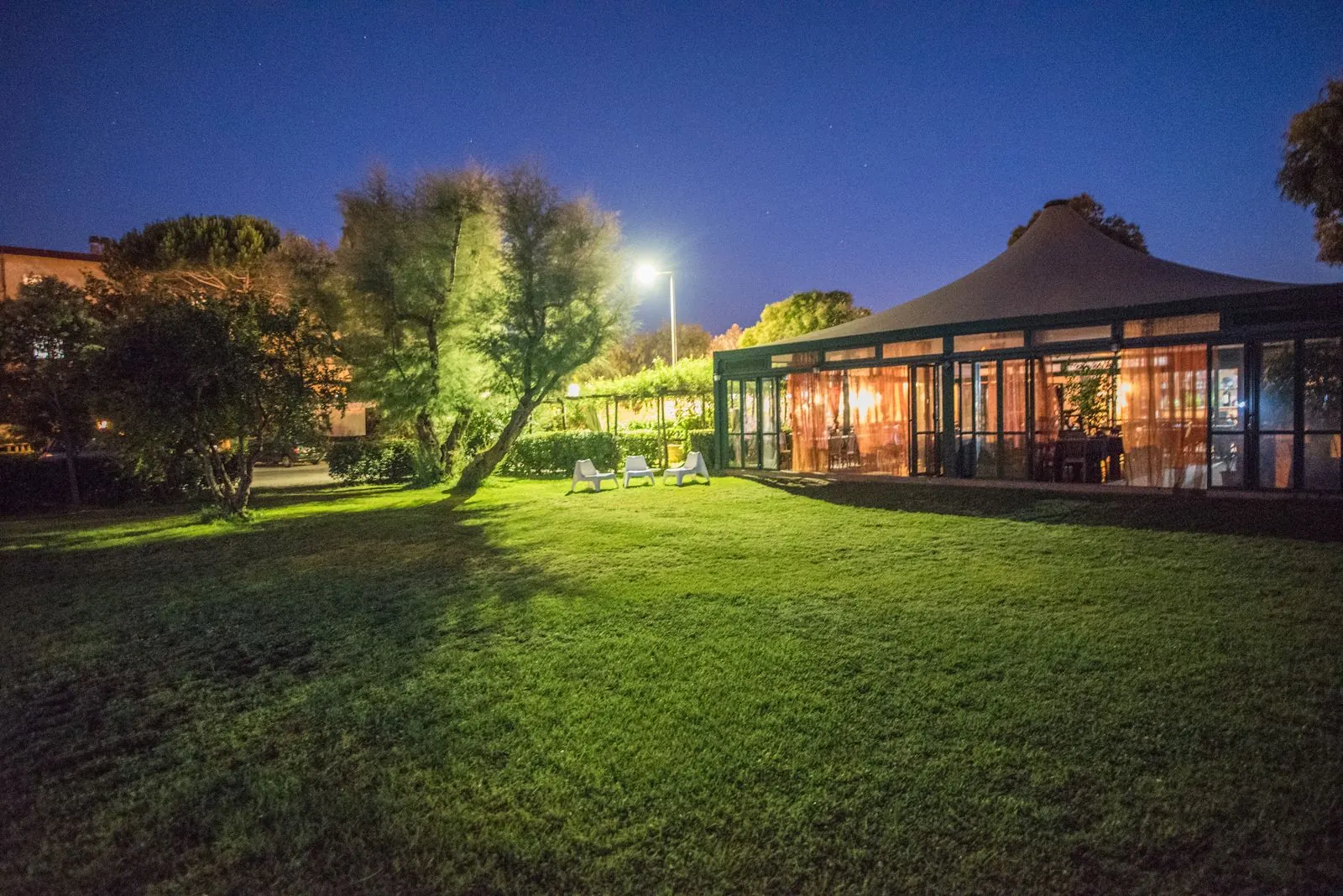 Il locale di notte visto dal prato illuminato
